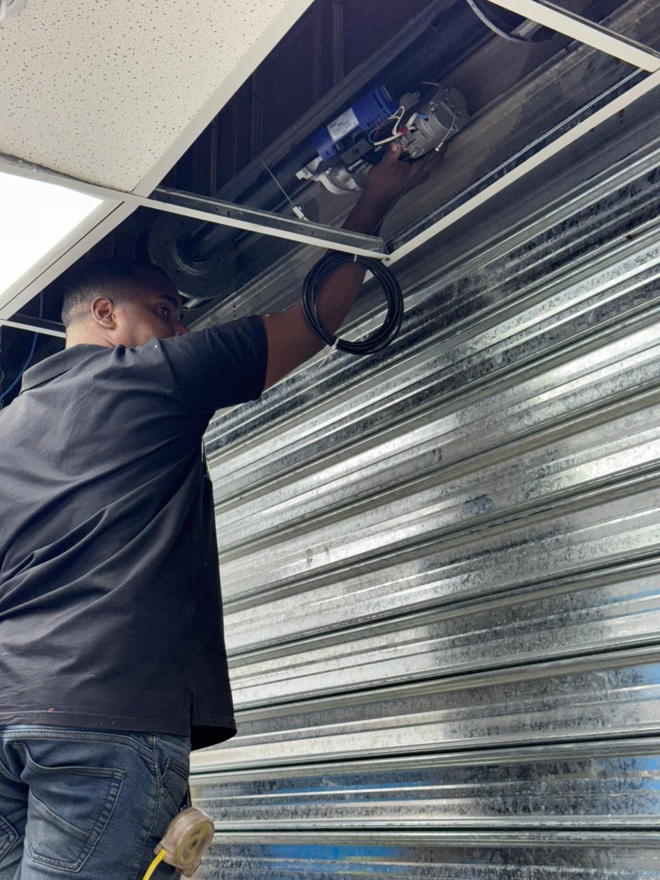Tecnico dando mantenimiento al motor de una puerta enrollable